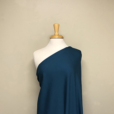 rayon knit fabric in teal drapped over a mannequin